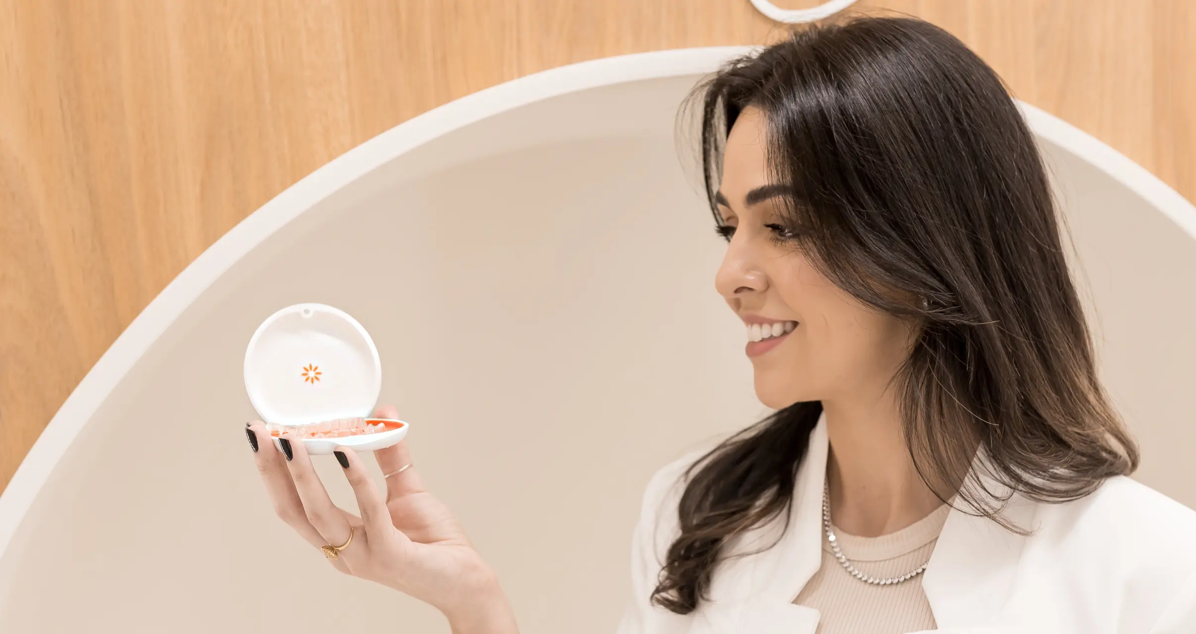 Dra. Bruna Rabaioli com um alinhador Invisalign, destacando o produto.